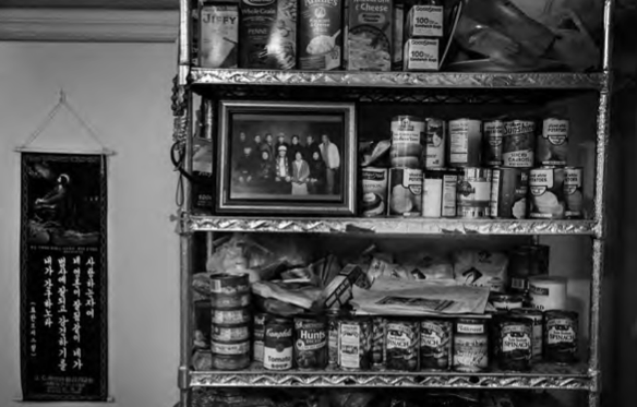 A shelf at the Love Mission House is stacked with cans of food and a group picture of the residents who regularly stay at the shelter. Photo by Yeong-Ung Yang. 